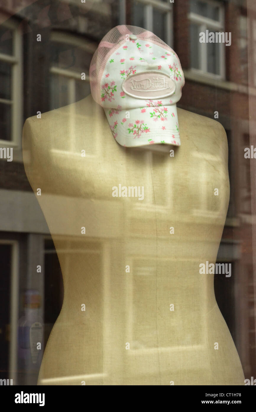Mannequin mit Kappe in Etalage mit Reflexionen von Windows aus dem gegenüberliegenden Gebäuden Stockfoto