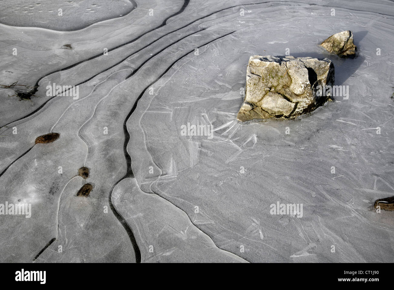 Steinen, eingehüllt in Mustern von Eiskristallen auf einen Pool von Wasser und Eis Stockfoto