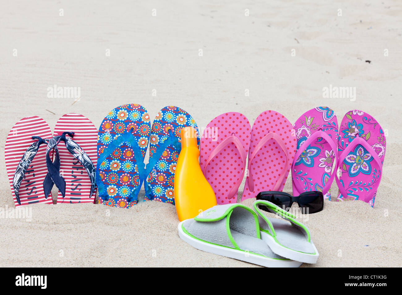 Vier Paare Bad Hausschuhe hintereinander stecken in den Sand Strand Stockfoto