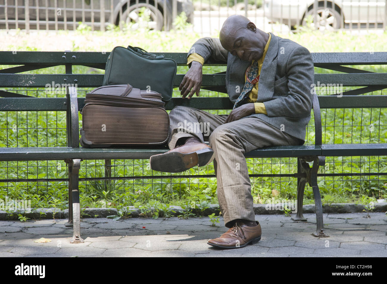 Mit seinen Habseligkeiten müde Mann schläft auf einer Parkbank im Central Park in New York City Stockfoto