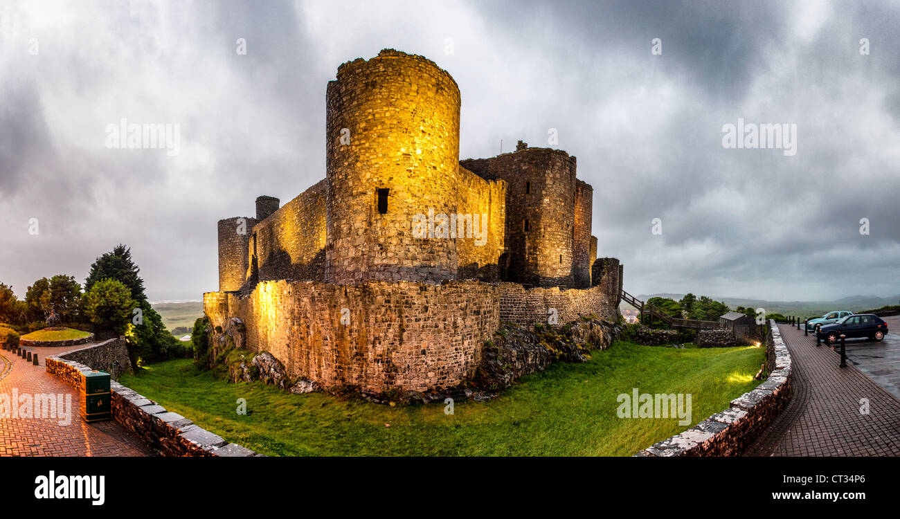 HARLECH, Wales – Harlech Castle steht im frühen Abendlicht dramatisch beleuchtet, seine imposanten mittelalterlichen Mauern und Türme bilden eine beeindruckende Silhouette vor dem dunkleren Himmel. Erbaut zwischen 1282 und 1289 von Eduard I. während seiner Eroberung von Wales, gilt dieses UNESCO-Weltkulturerbe als eines der schönsten Beispiele für Militärarchitektur des späten 13. Jahrhunderts in Europa. Die Festung nimmt eine strategische Position auf einem Felsvorsprung ein, der die Cardigan Bay überblickt, wobei die Berge von Snowdonia in der Ferne sichtbar sind. Einst fast uneinnehmbar wegen seiner Klippenlage und Meeresnähe Stockfoto