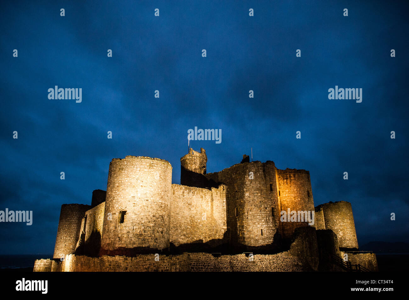 HARLECH, Wales – Harlech Castle, eine Festung aus dem 13. Jahrhundert, die von Eduard I. erbaut wurde, steht an der Nordwestküste von Wales vor dem Abendhimmel. Das verblassende Licht unterstreicht die imposante Umrisse dieses UNESCO-Weltkulturerbes, zeigt seine strategische Lage mit Blick auf die Irische See und erinnert an die mittelalterliche Pracht dieses historischen Denkmals. Stockfoto