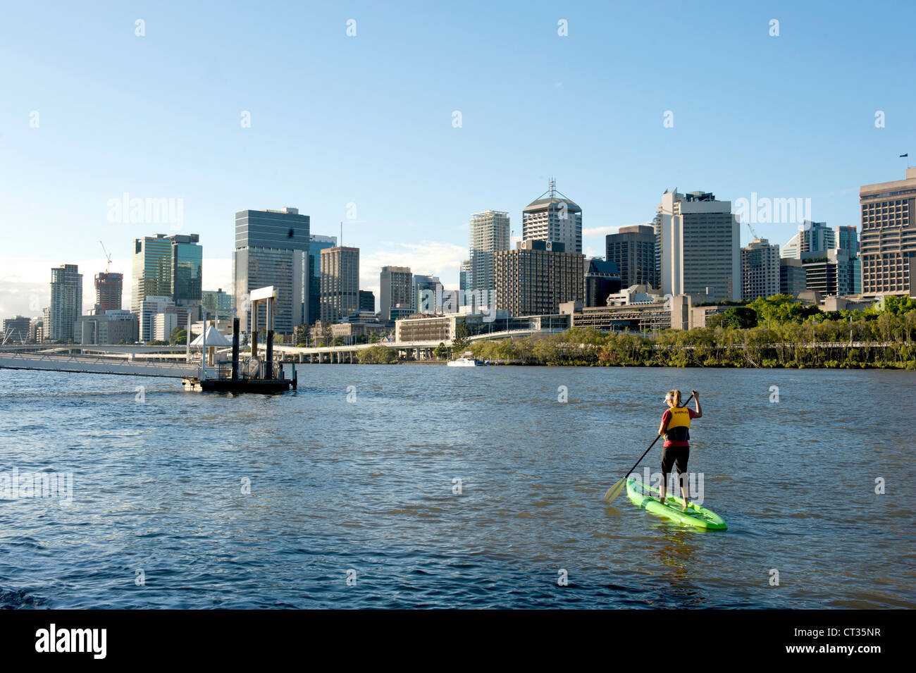 Eine Frau tun Stand-Up Paddeln am Brisbane River mit der CBD, Queensland, Australien Stockfoto