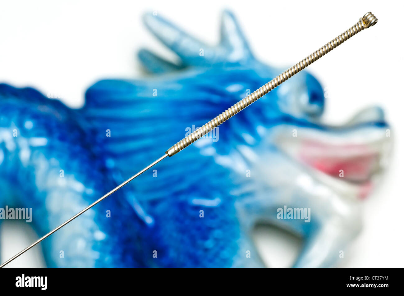 Akupunktur-Nadel über einer blauen Drachen Figur Stockfoto