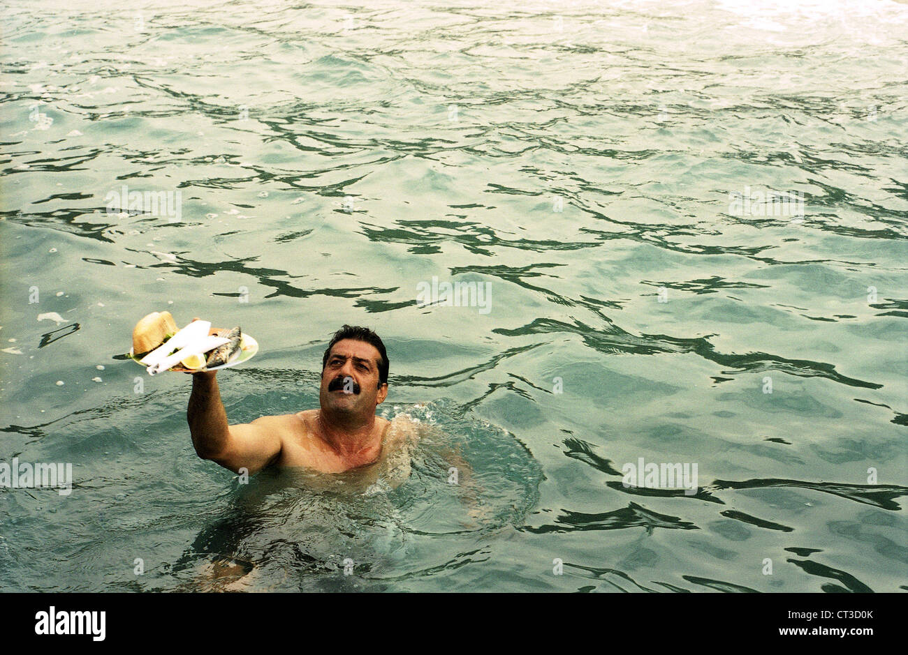 Alanya, schwimmt Man im Meer mit einem vollen Teller Stockfoto