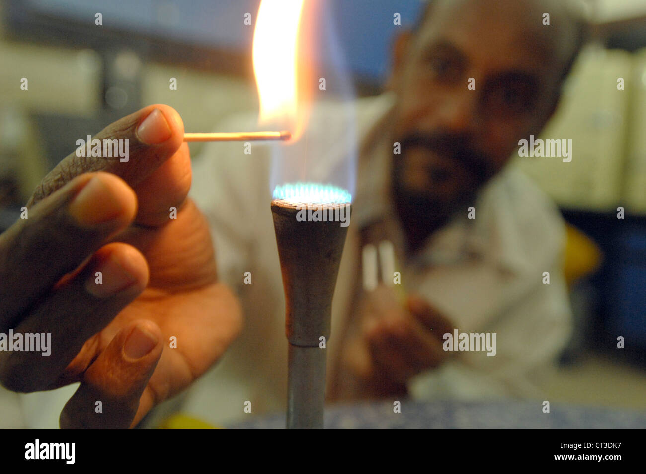 Ein Labortechniker Beleuchtung ein Bunsenbrenner mit einem Streichholz. Stockfoto