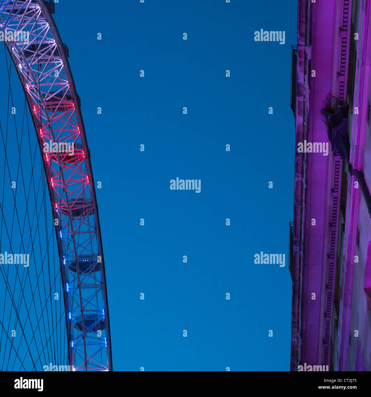 Das ikonische London Eye beleuchtet in rot, weiß und blau in der Nacht mit Flutlicht auf County Hall Gebäude im zentralen London, UK Stockfoto