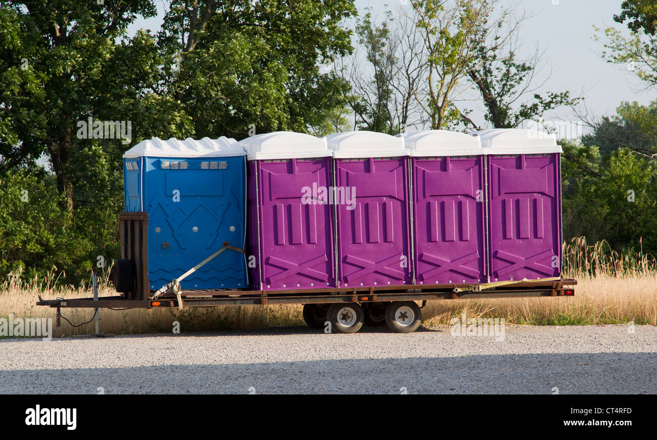 Eine Reihe von blau und lila Porta potty WC auf einem Anhänger zu einem Termin versandfertig. Stockfoto