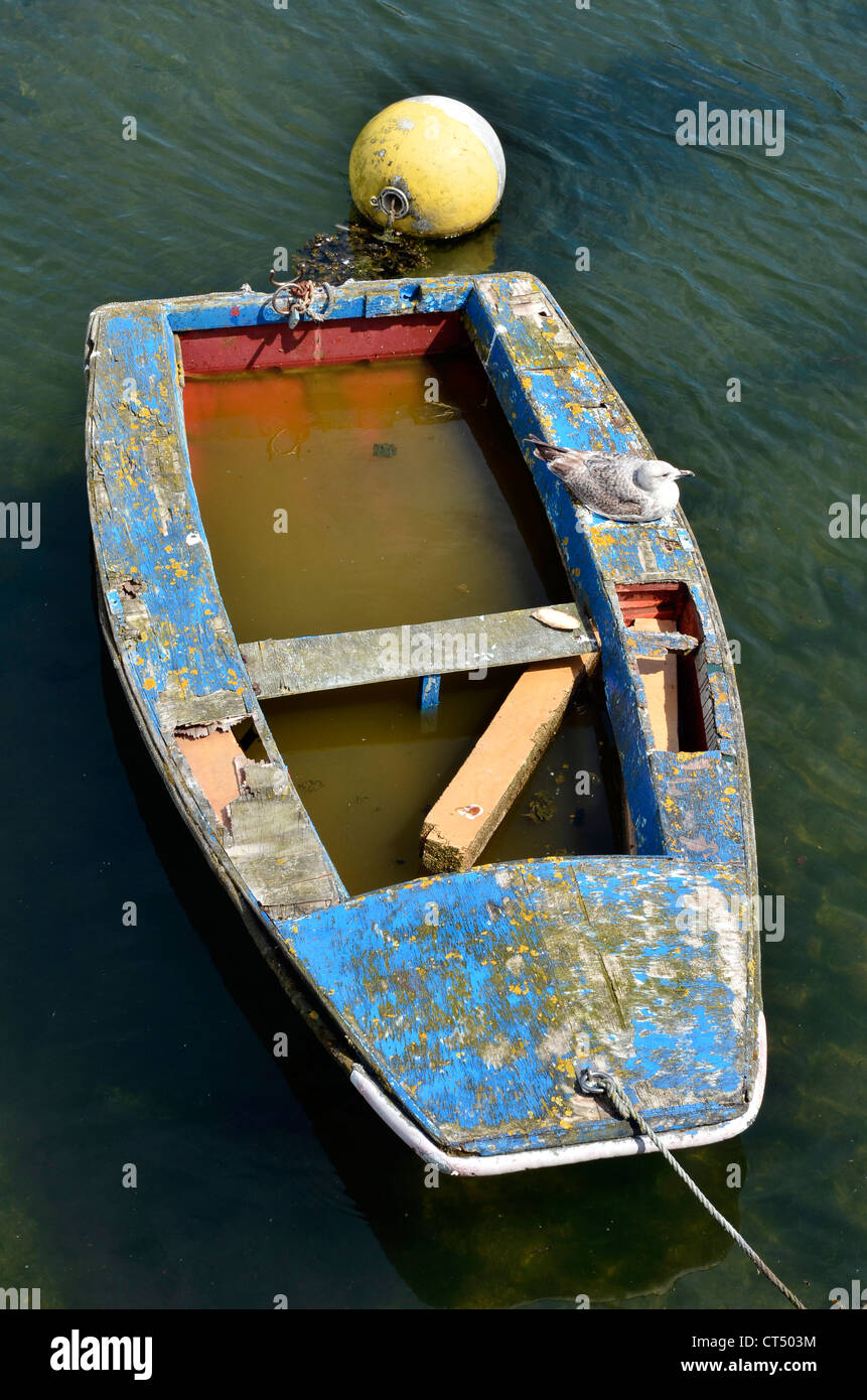 Alte kleine Boot durch das Wasser im Inneren und eine Möwe liegen, gesehen von oben, an der Küste der Bretagne in Frankreich Stockfoto