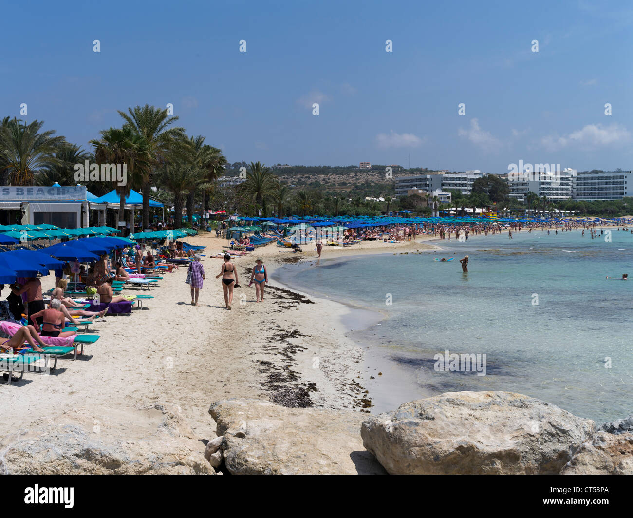 dh Liminaki Strand AYIA NAPA ZYPERN Blaue Sonnenschirme Futter weiß Sand Strand Touristen Badegäste und Hotels südlich Stockfoto