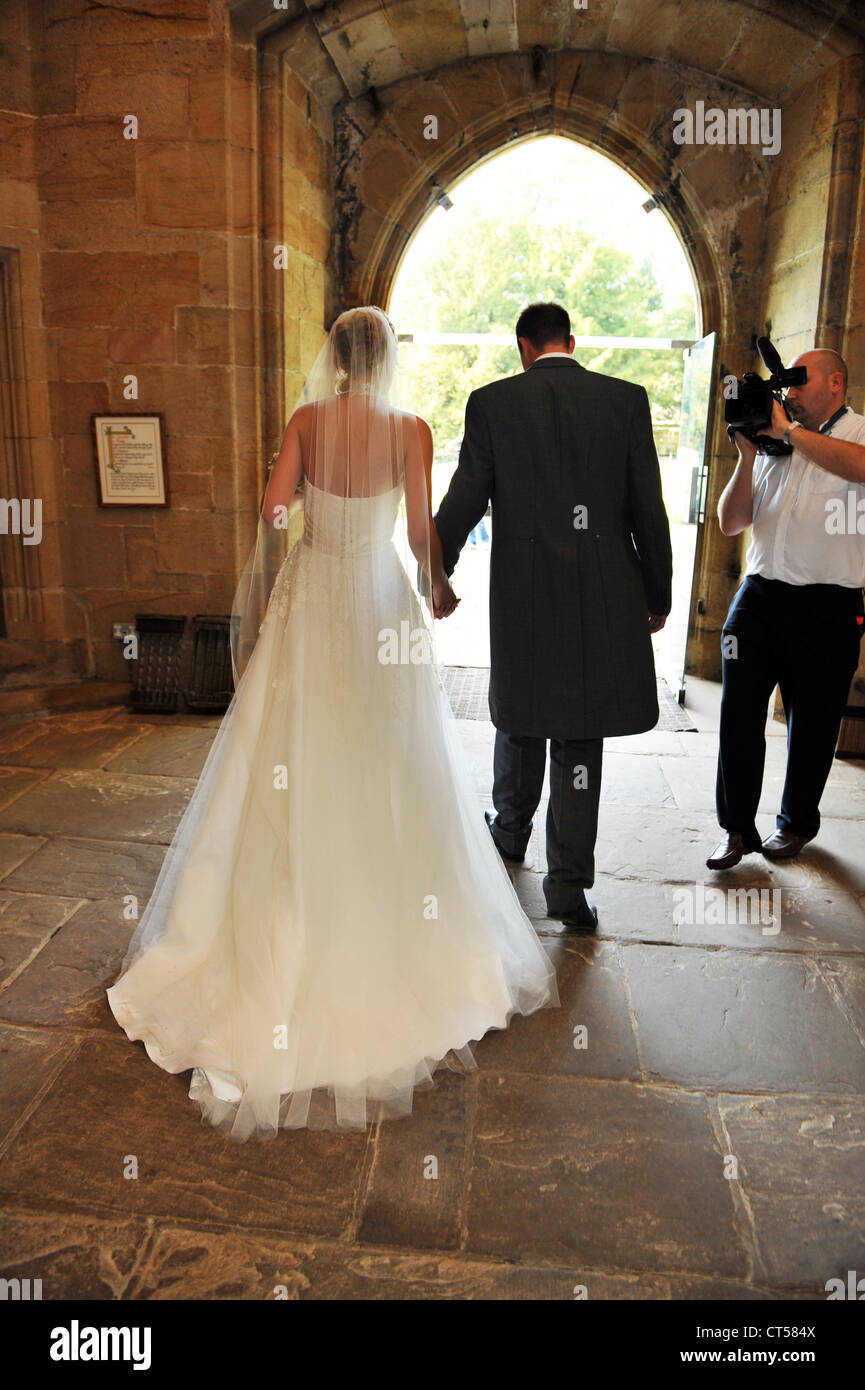Eine Braut und Bräutigam verlassen die Kirche, während auf Video gefilmt. Stockfoto