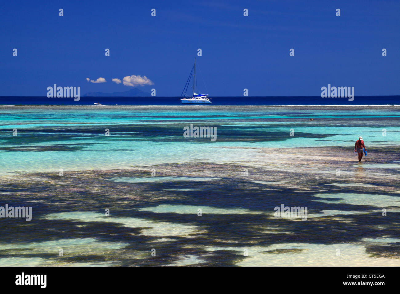 Mann an Land waten vom Segelboot in der Nähe von Anse Source d ' Argent, La Digue, Seychellen, Indischer Ozean auf La Digue auf den Seychellen Stockfoto