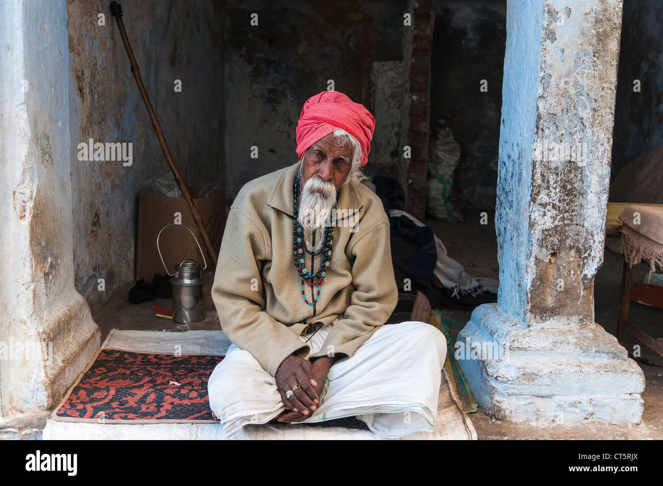 Alten indischen Mann mit einem roten Turban, sitzt vor einer Tür, Pushkar, Rajasthan, Indien Stockfoto