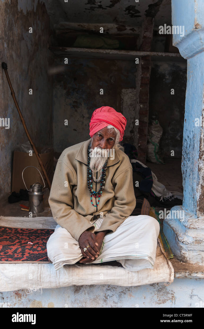 Alten indischen Mann mit einem roten Turban, sitzt vor einer Tür, Pushkar, Rajasthan, Indien Stockfoto