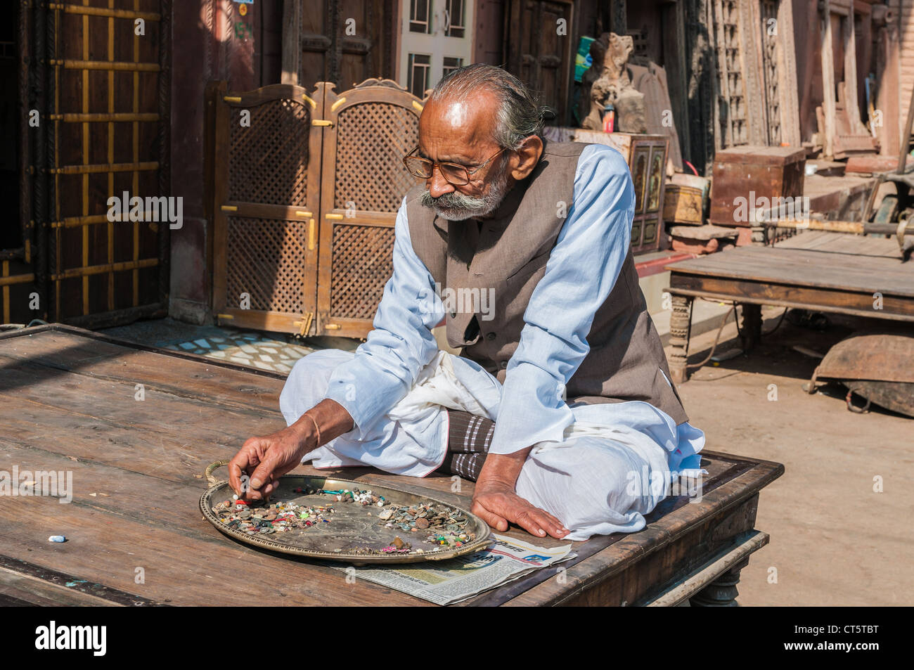 Alten indischen Mann sitzend, verschiedene Knöpfe und Kurzwaren, Rajasthan, Indien Stockfoto