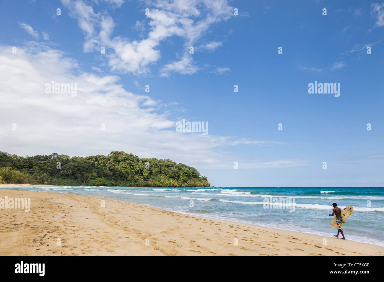 Surfer zu Fuß entlang des Meeres an Assistenten Strand (erste) auf Isla Bastimentos, Bocas del Toro, Panama. Stockfoto
