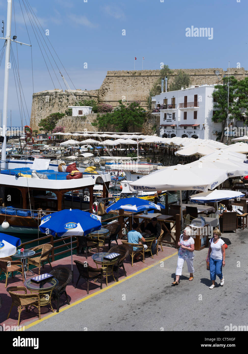 dh Girne Old Harbour KYRENIA NORD-NORDZYPERN Touristen Frauen Spaziergang am Kai Restaurant Tische Cafe Tourismus Stockfoto