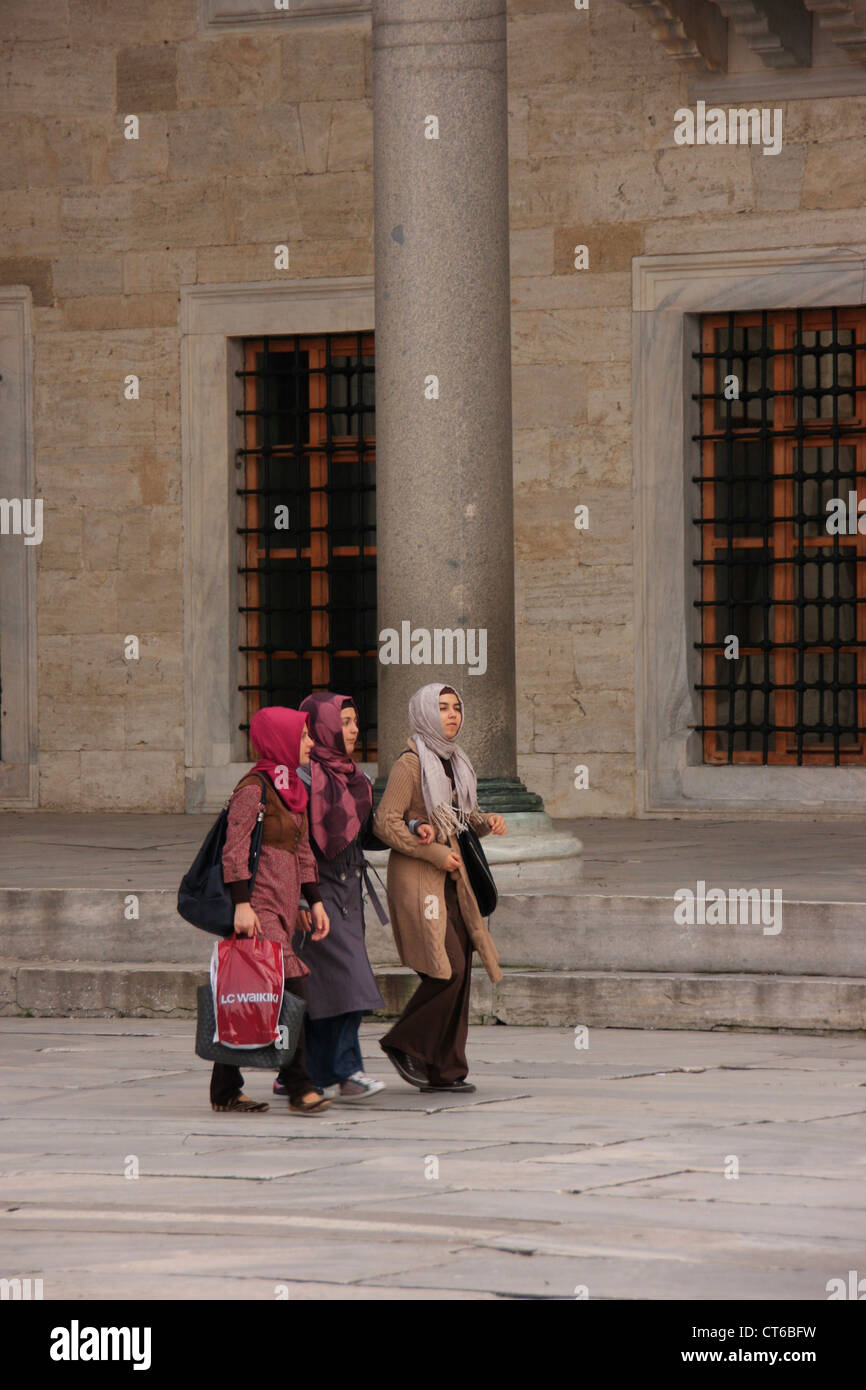 Junge muslimische Frauen gehen in den Innenhof des Sultan Ahmed Mosque, Sultanahmet, Istanbul, Türkei Stockfoto