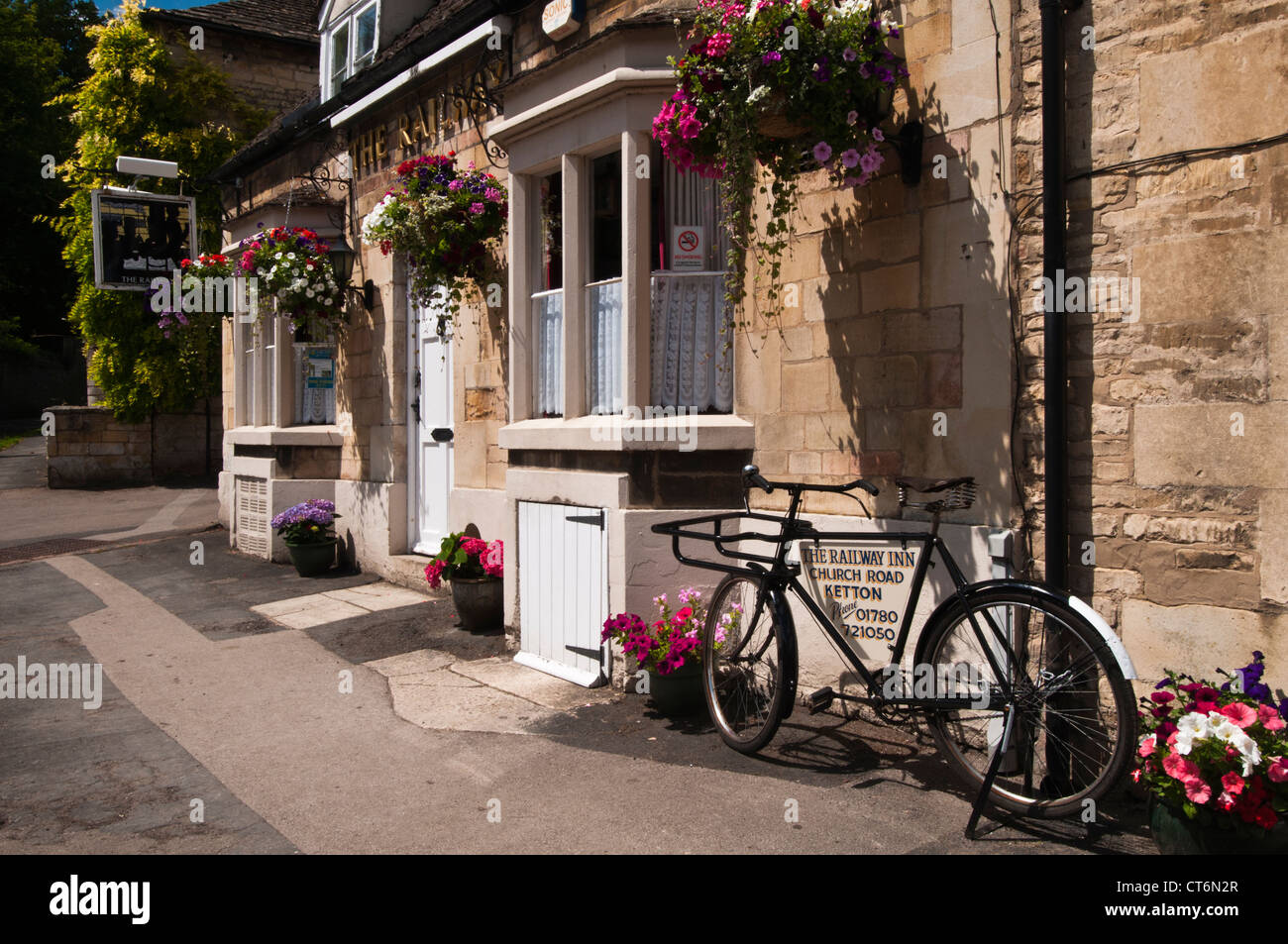 Railway Inn mit bunten Blumenampeln und Töpfe in Church Road, Ketton, Rutland, England Stockfoto