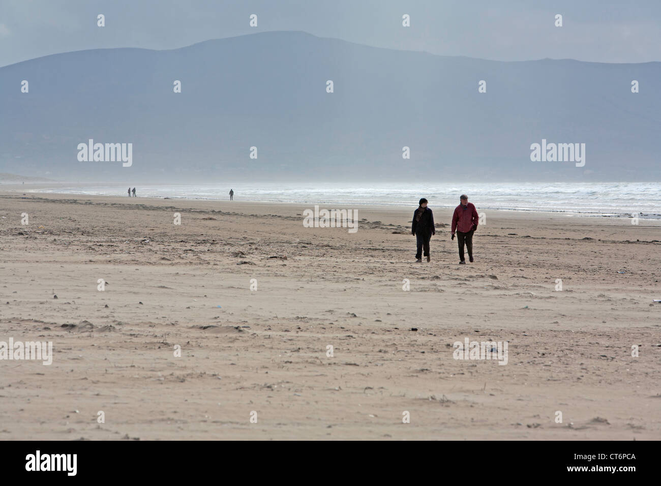 Paare, die auf einem windigen Inch Strand mit anderen im Hintergrund Stockfoto