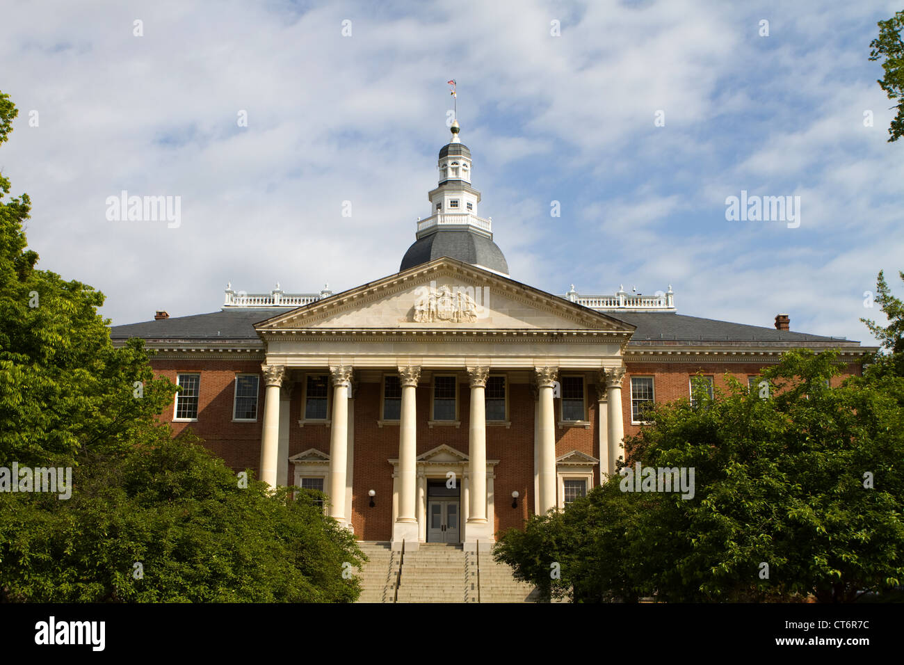 Maryland State Capitol Gebäude mit Kuppel vor einem bewölkten blauen Himmel mit den umliegenden Bäumen in Annapolis, Maryland, USA. Stockfoto
