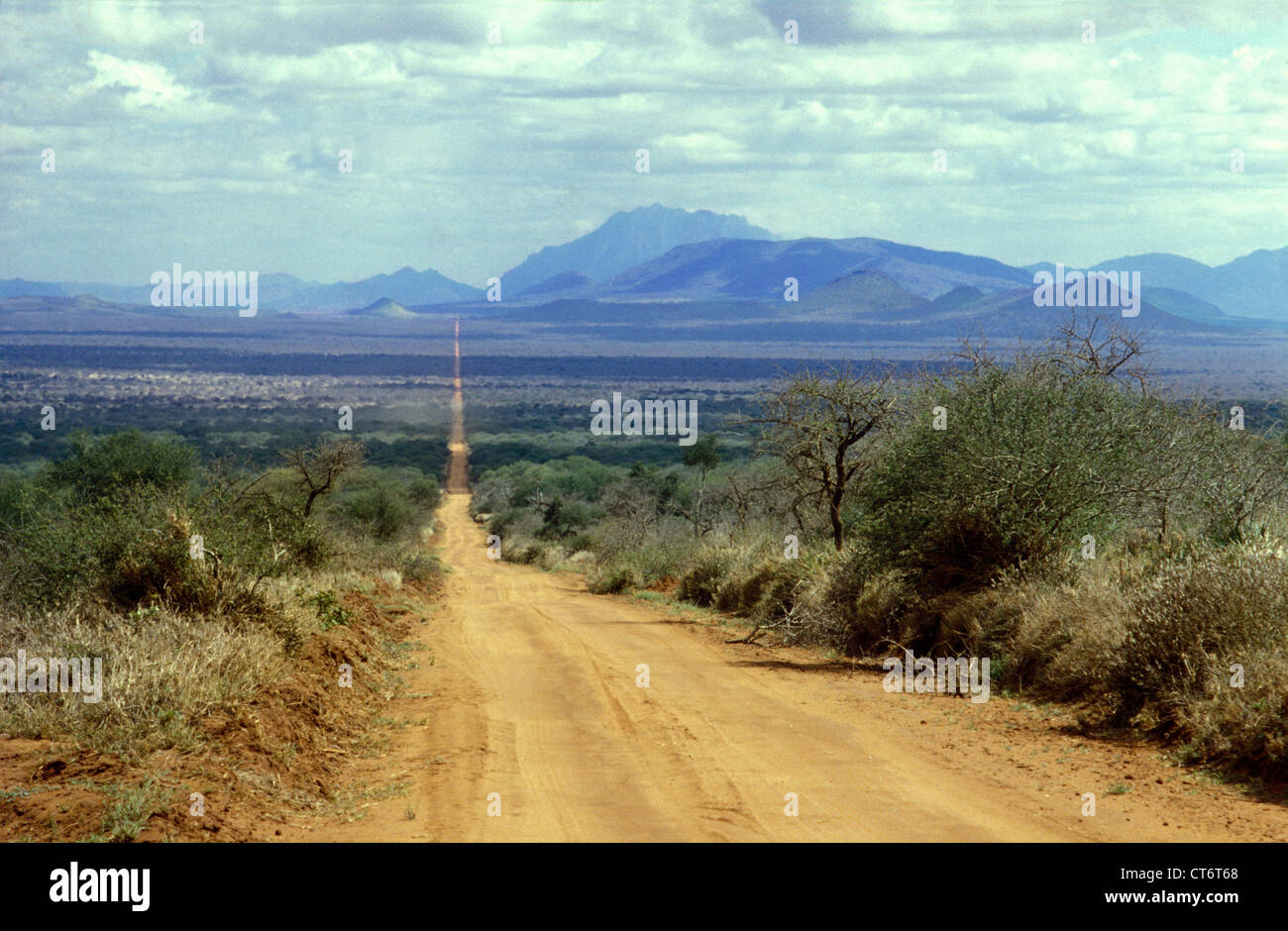 Straße in Tsavo West Nationalpark, Kenia, Ostafrika. Taita Hills in der Ferne. Stockfoto