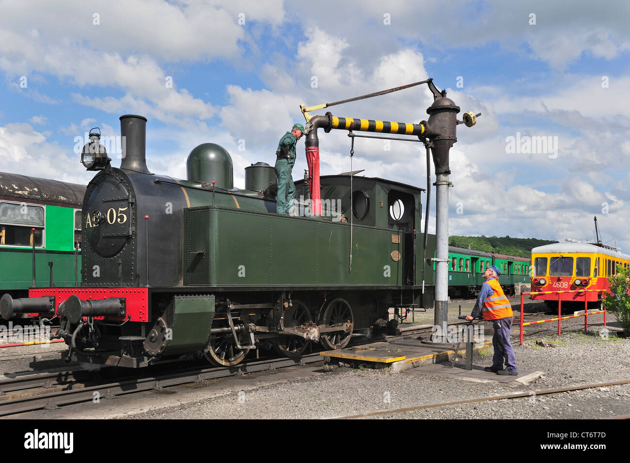 Lokführer und Crew füllen Kessel der Dampflok von Wasserkran im Depot des Trois Vallées in Mariembourg, Belgien Stockfoto