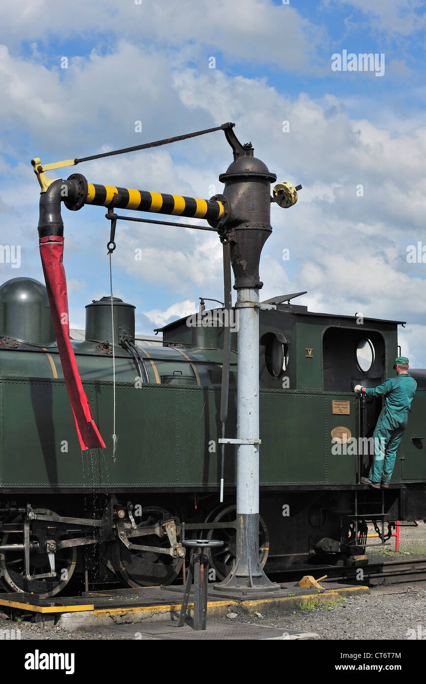 Lokführer Füllung Kessel der Dampflok von Wasserkran im Depot des Trois Vallées in Mariembourg, Belgien Stockfoto