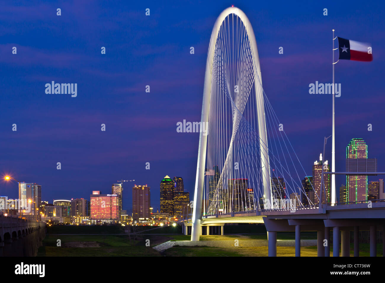 Die neue (2012) Margaret Hunt Hill Bridge, entworfen von Santiago Calatrava mit Nachtbeleuchtung von Dallas, Texas in den Hintergrund. Stockfoto