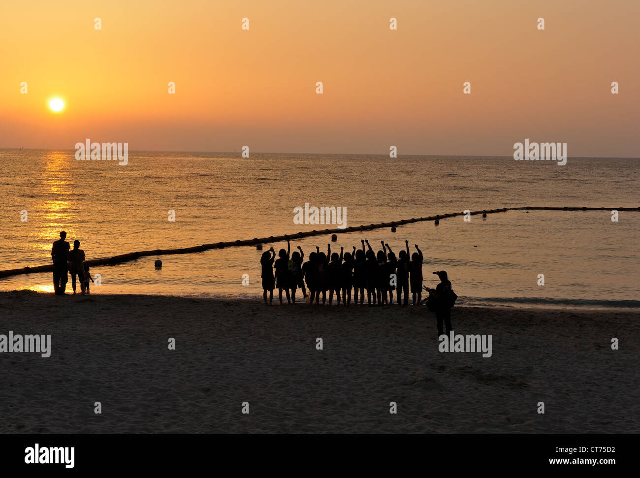 Eine Gruppe Teenager jubeln den wunderschönen Sonnenuntergang und der Gedanke der Sommer endlich angekommen in Okinawa, Japan. Stockfoto