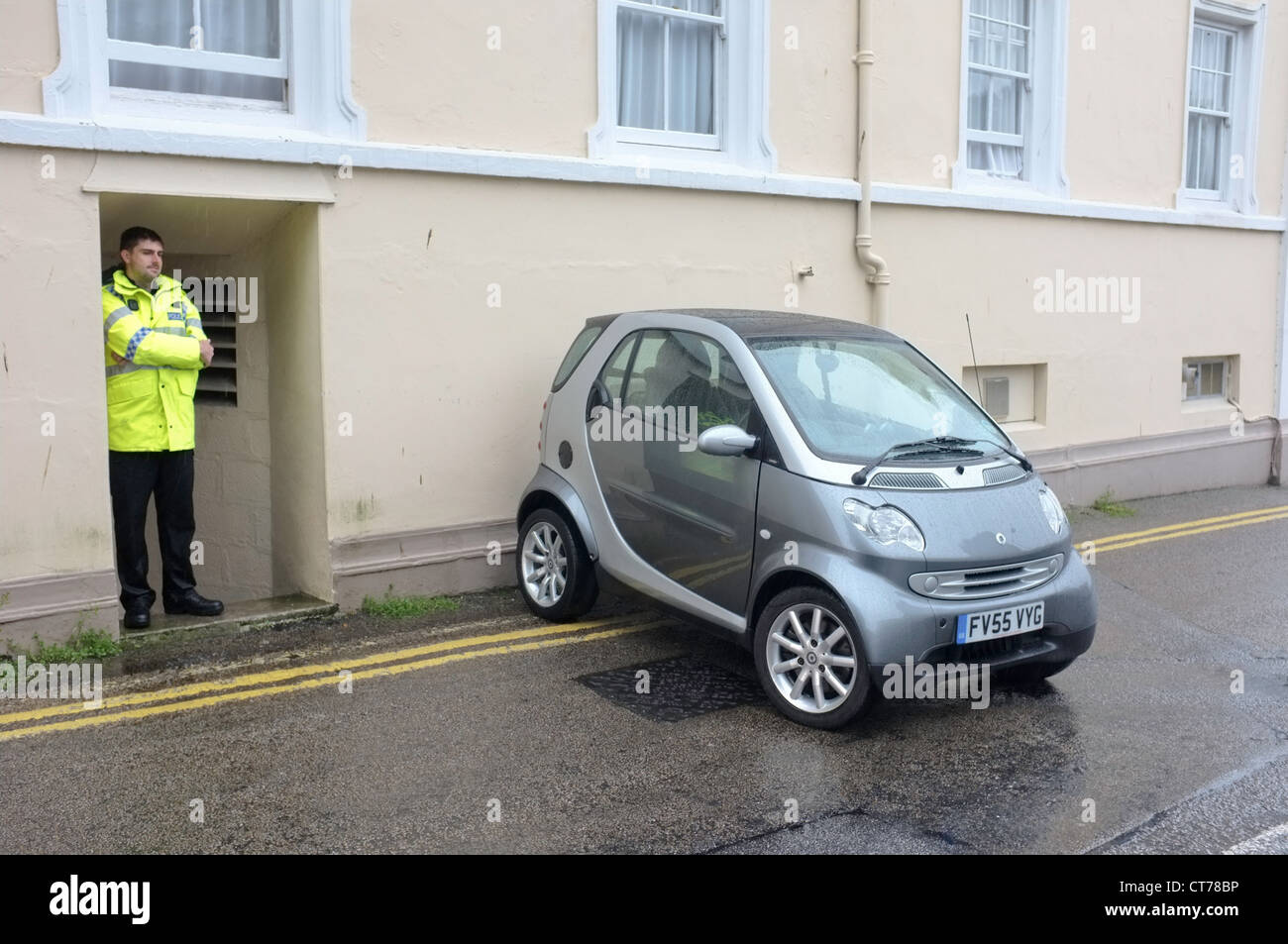 Ein schlecht geparktes Auto bewacht von einem Polizisten in Falmouth, Cornwall Stockfoto