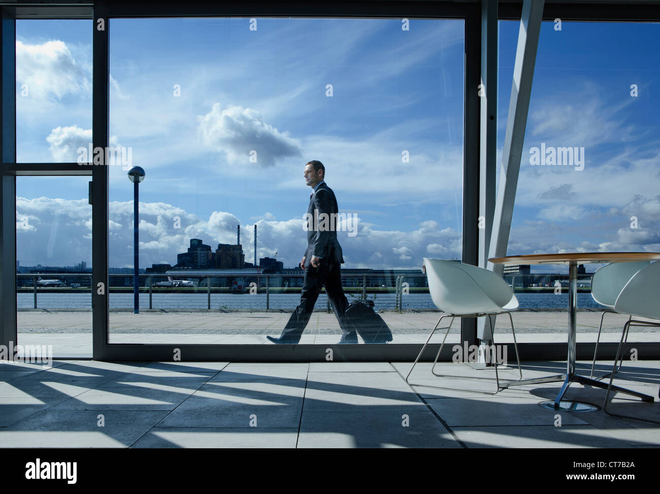 Geschäftsmann zu Fuß mit Koffer vor Flughafen Stockfoto