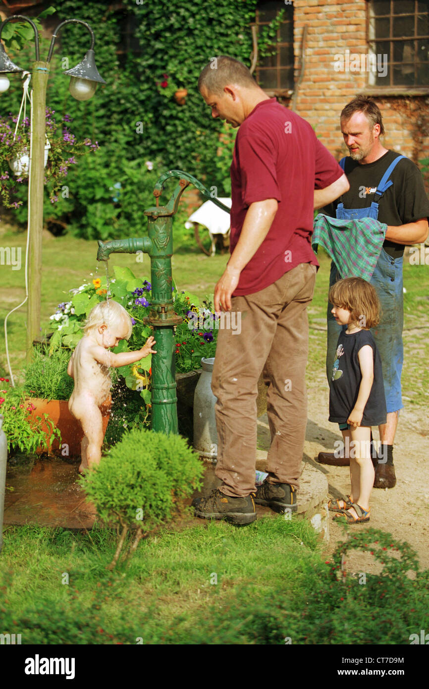 Ein Kind nimmt eine kalte Dusche im Garten Stockfoto
