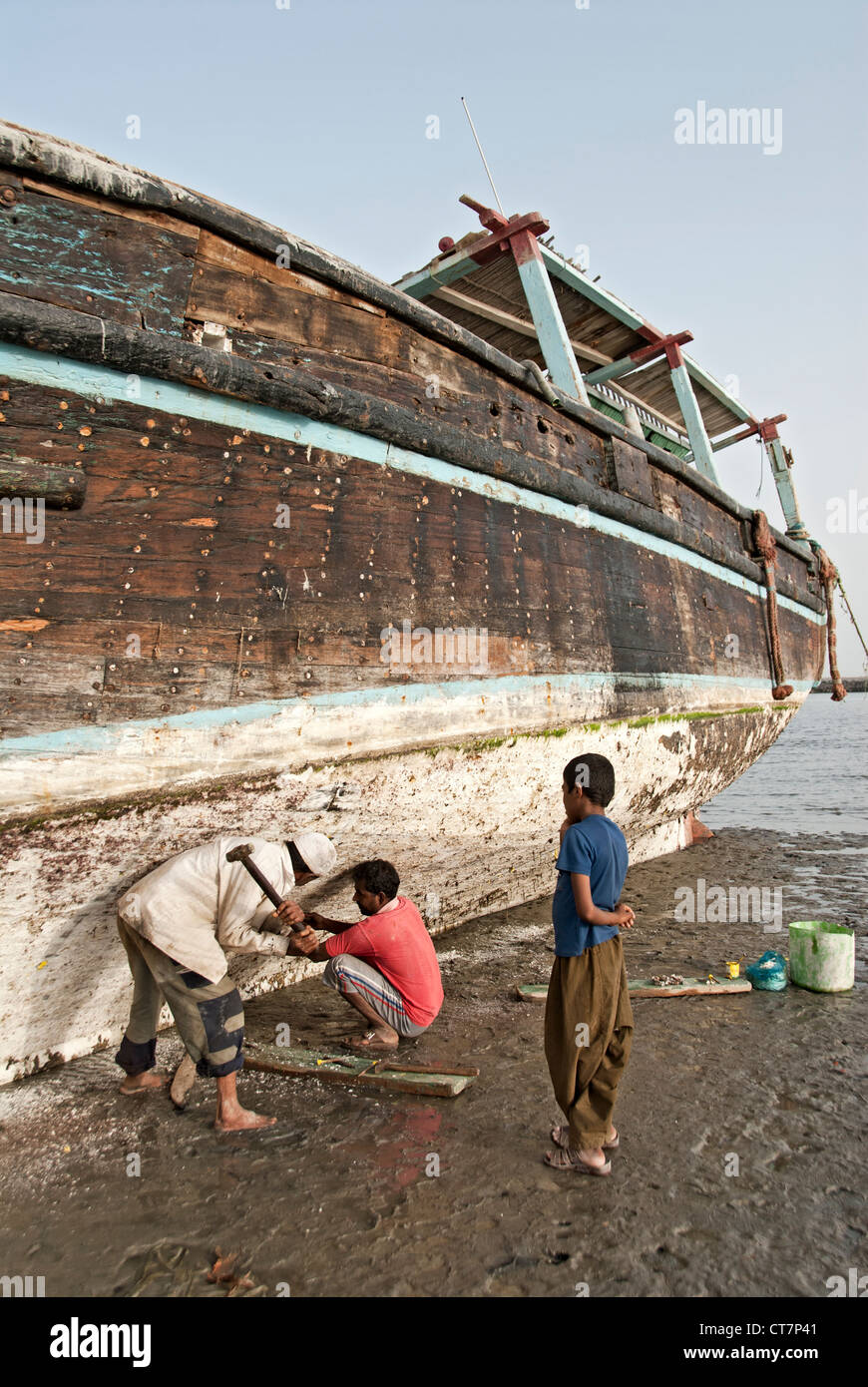 Menschen vor Ort Reparatur ein Fischerboot verankert auf dem Sand, Bandar Abbas, Iran Stockfoto