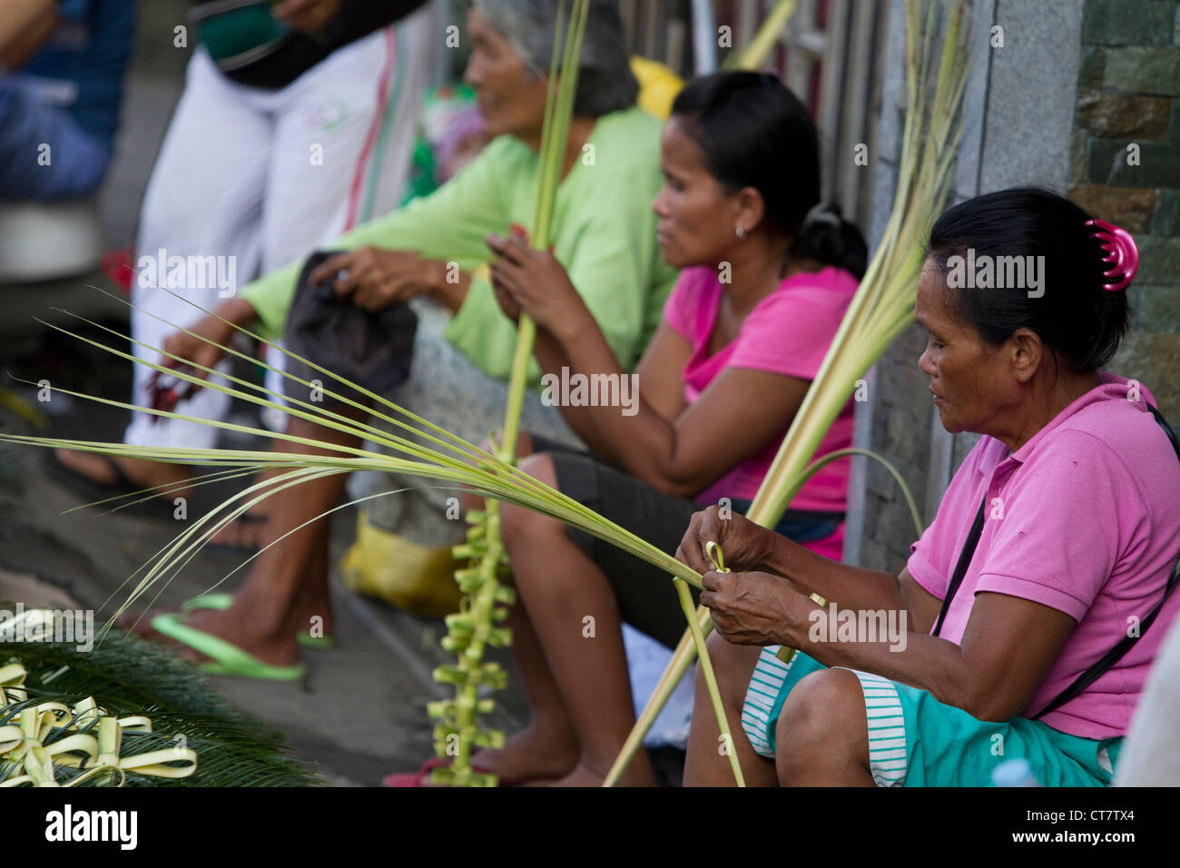 Cebu City, Philippinen - Frauen machen Kreuze aus Palm verlässt zu Beginn der Karwoche 2012 Stockfoto