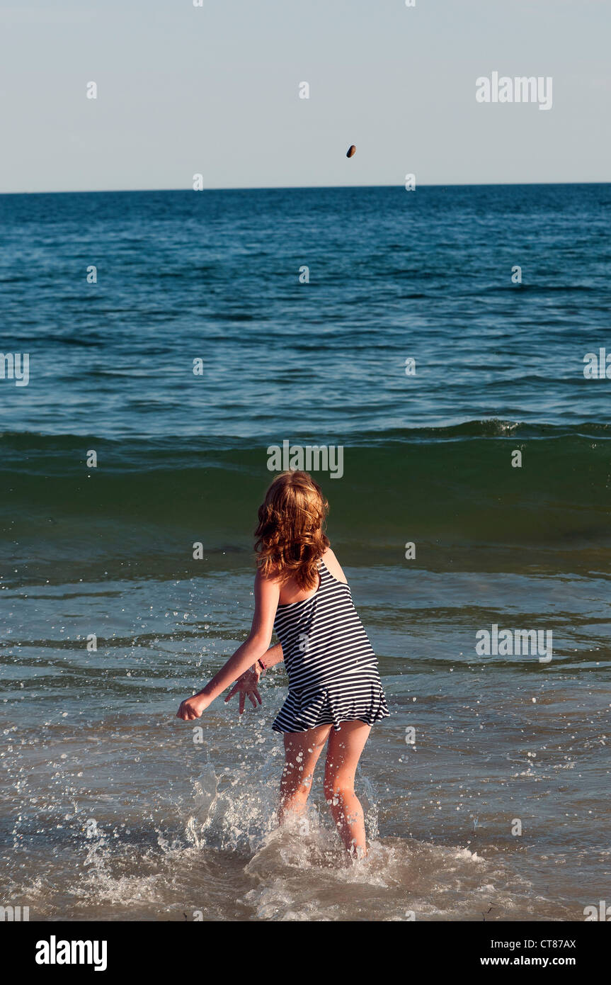Junges Mädchen Felsen ins Meer werfen Stockfoto