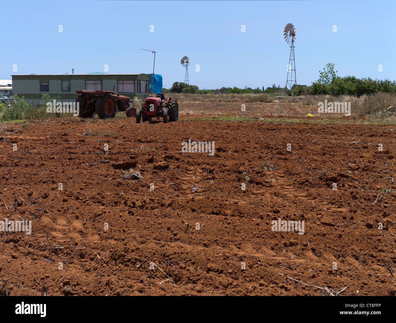 dh AYIA NAPA Bereich Zypern Farm rote Erde Feld Ackerland Traktoren Wohnwagen Windmühle Wasser Pumpe Süden Stockfoto