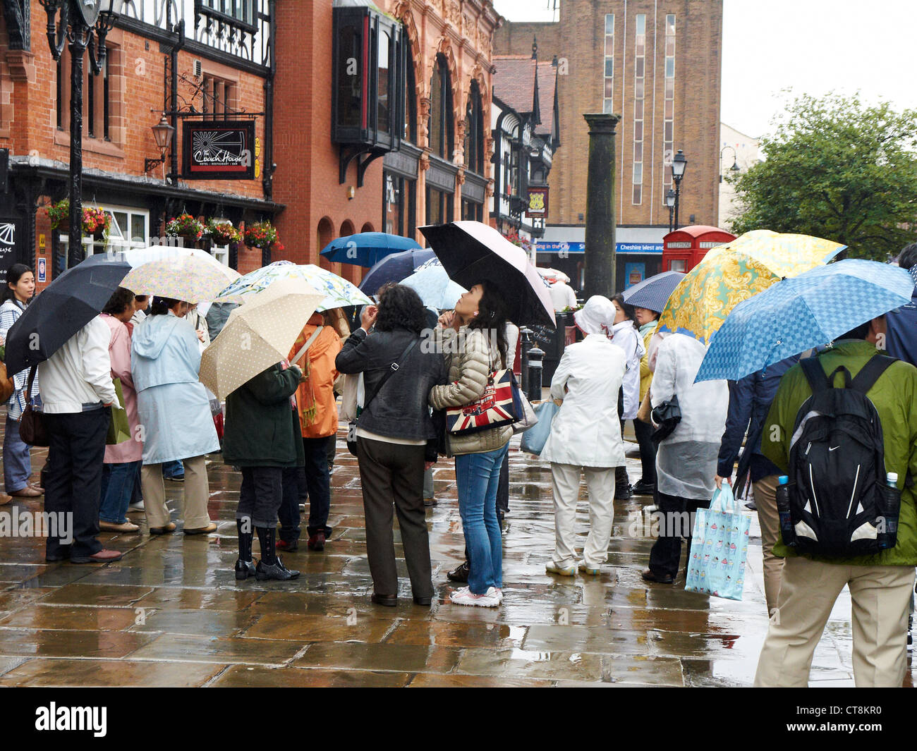 Japanische Touristen stehen im strömenden Regen vor Chester Rathaus, Chester, Cheshire UK Stockfoto