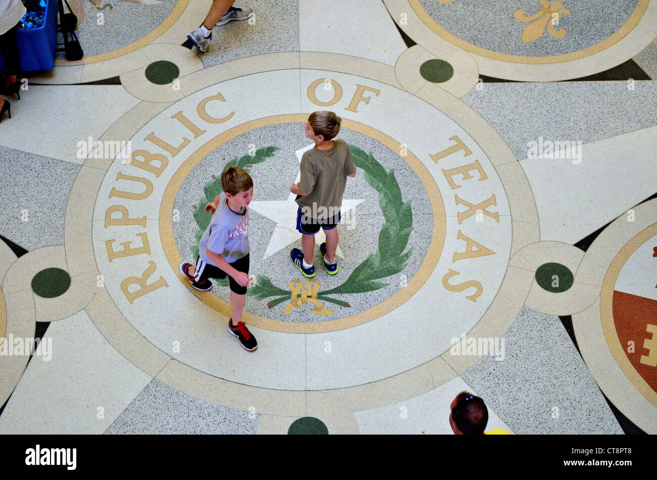 Zwei Jungs, die zu Fuß über die Republik Texas-Emblem im Inneren des Gebäudes der Landeshauptstadt. Austin, Texas, USA. Stockfoto