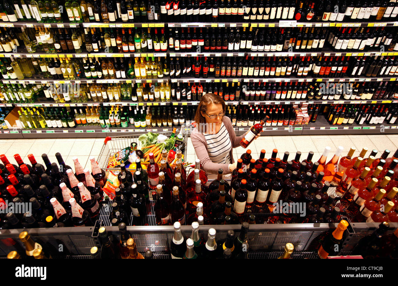 Frau ist in einem großen Supermarkt einkaufen. Getränkeabteilung, alkoholische Getränke, Spirituosen, Wein, Champagner. Stockfoto