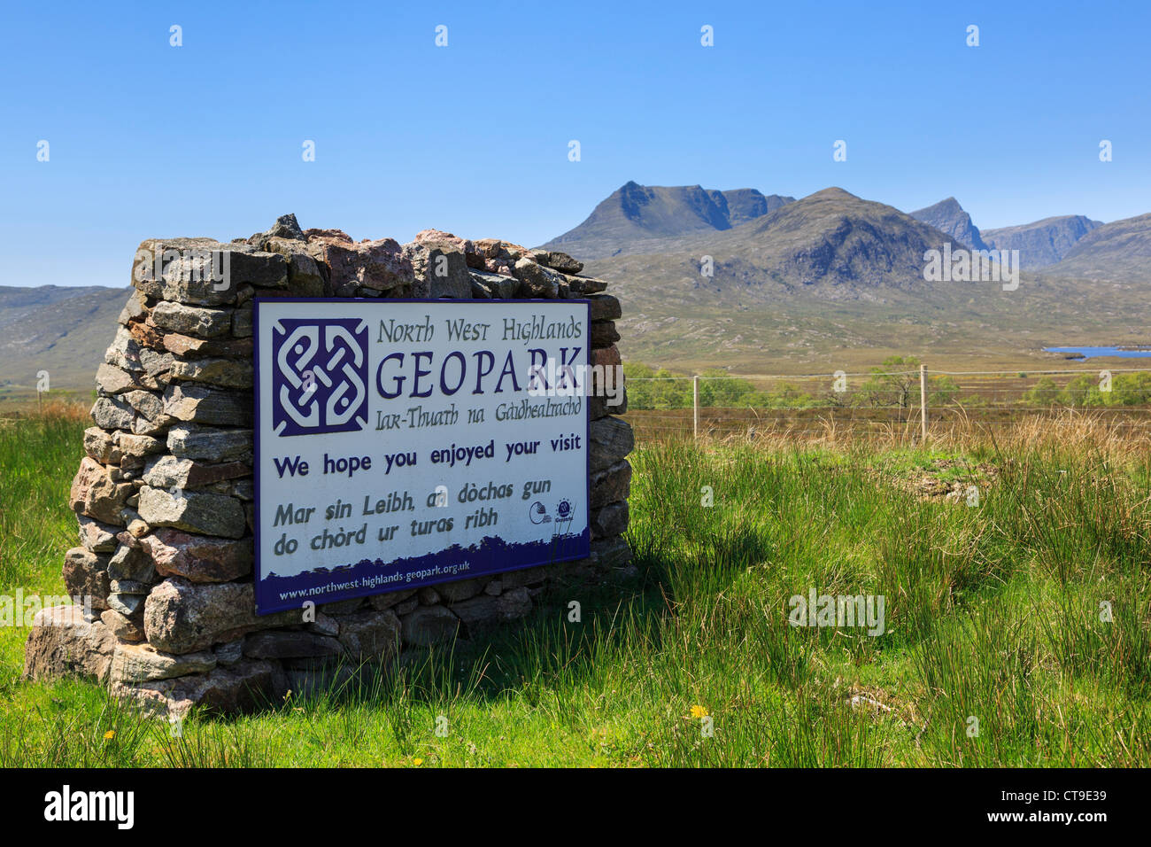 North West Highlands Geopark Gaelic Zweisprachiges Schild mit Ben More Coigach Berg darüber hinaus. Assynt, Ross und Cromarty, Scottish Highlands, Schottland, UK Stockfoto