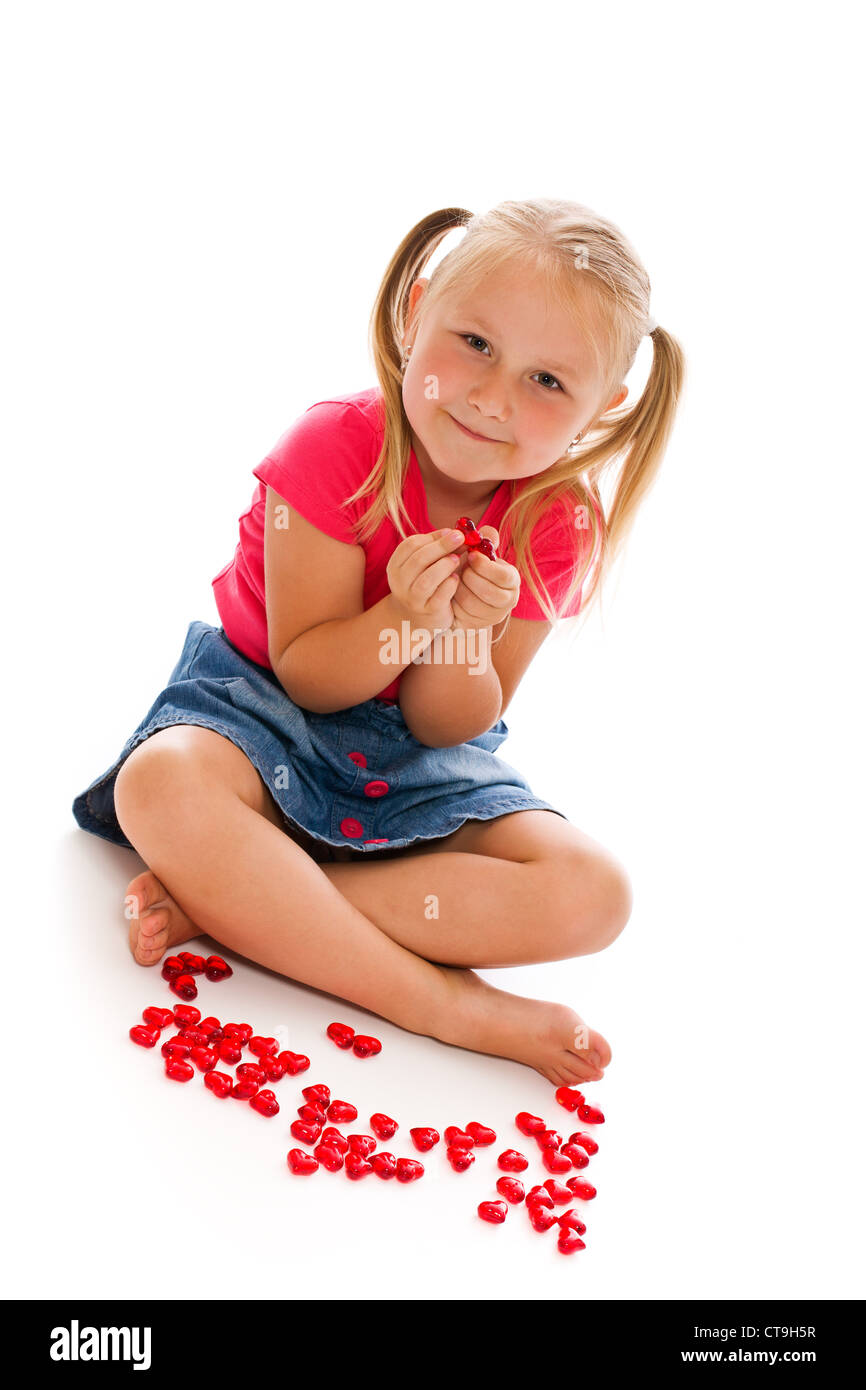kleines Mädchen sitzen auf weißen Boden mit roten Herzen Stockfoto
