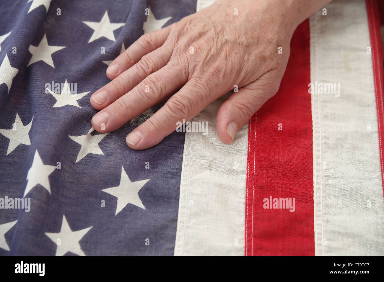 die Hand eines Mannes auf eine sehr alte amerikanische Flagge Stockfoto