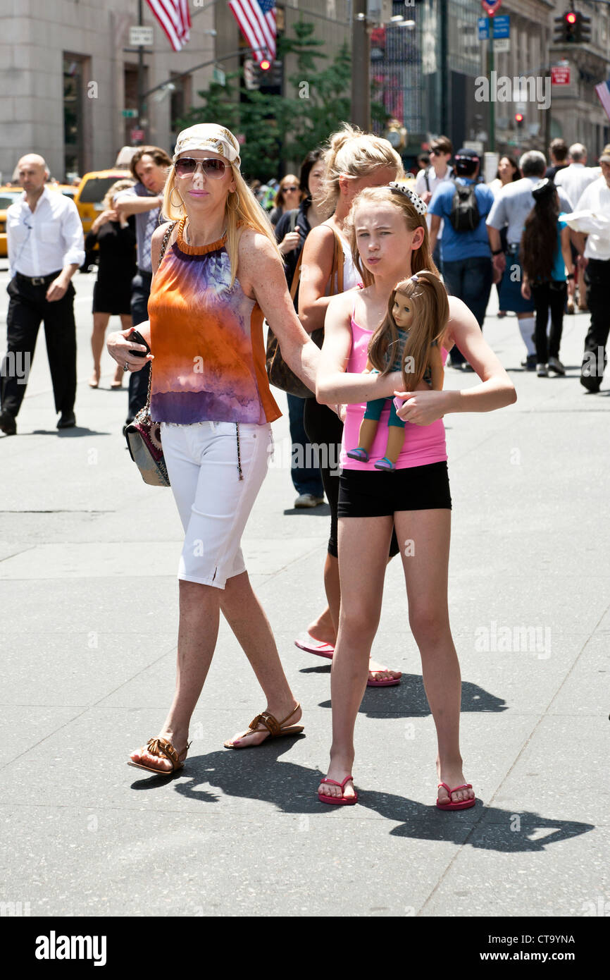 schicke Großmutter mit hohen junge Enkelin Barbie Art-Puppe an heißen Tag in Midtown Manhattan an der Fifth Avenue spazieren tragen Stockfoto