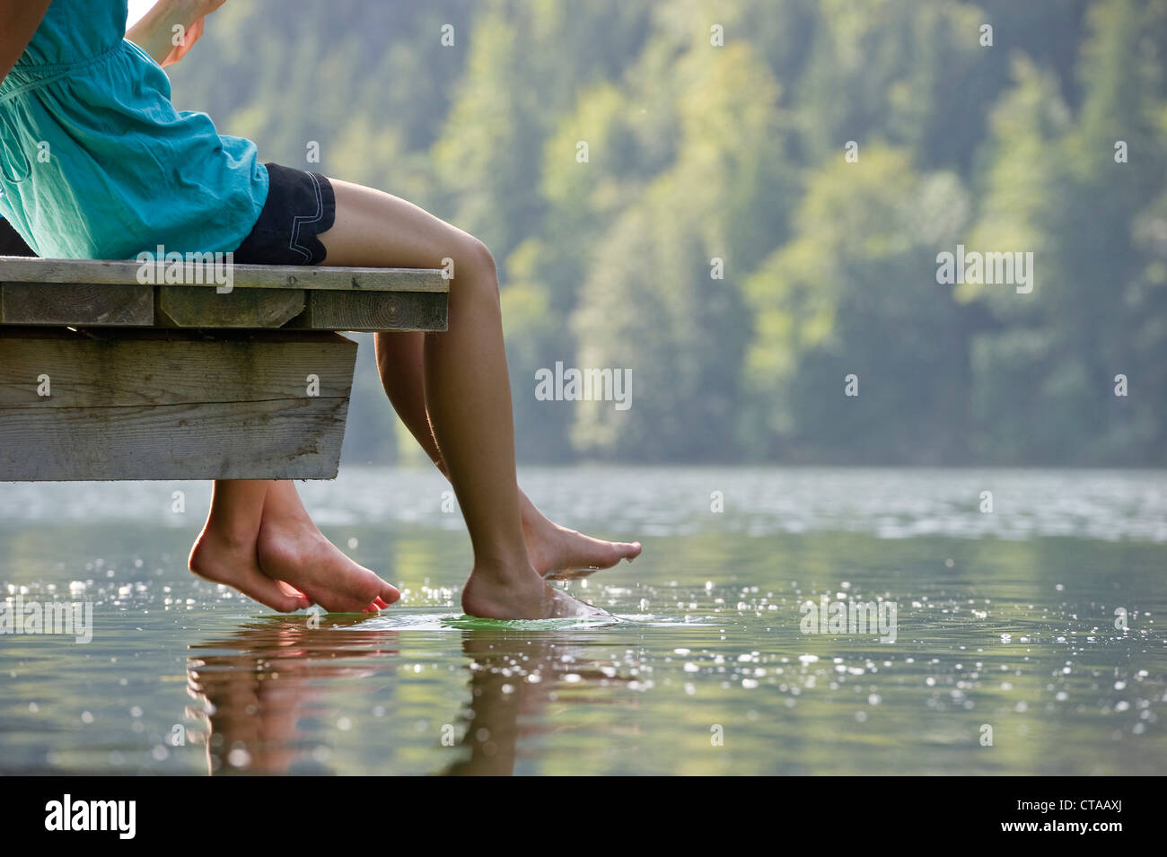 Zwei Mädchen sitzen auf einem Steg am See Schwansee, Schwangau, Allgäu, Bayern, Deutschland Stockfoto