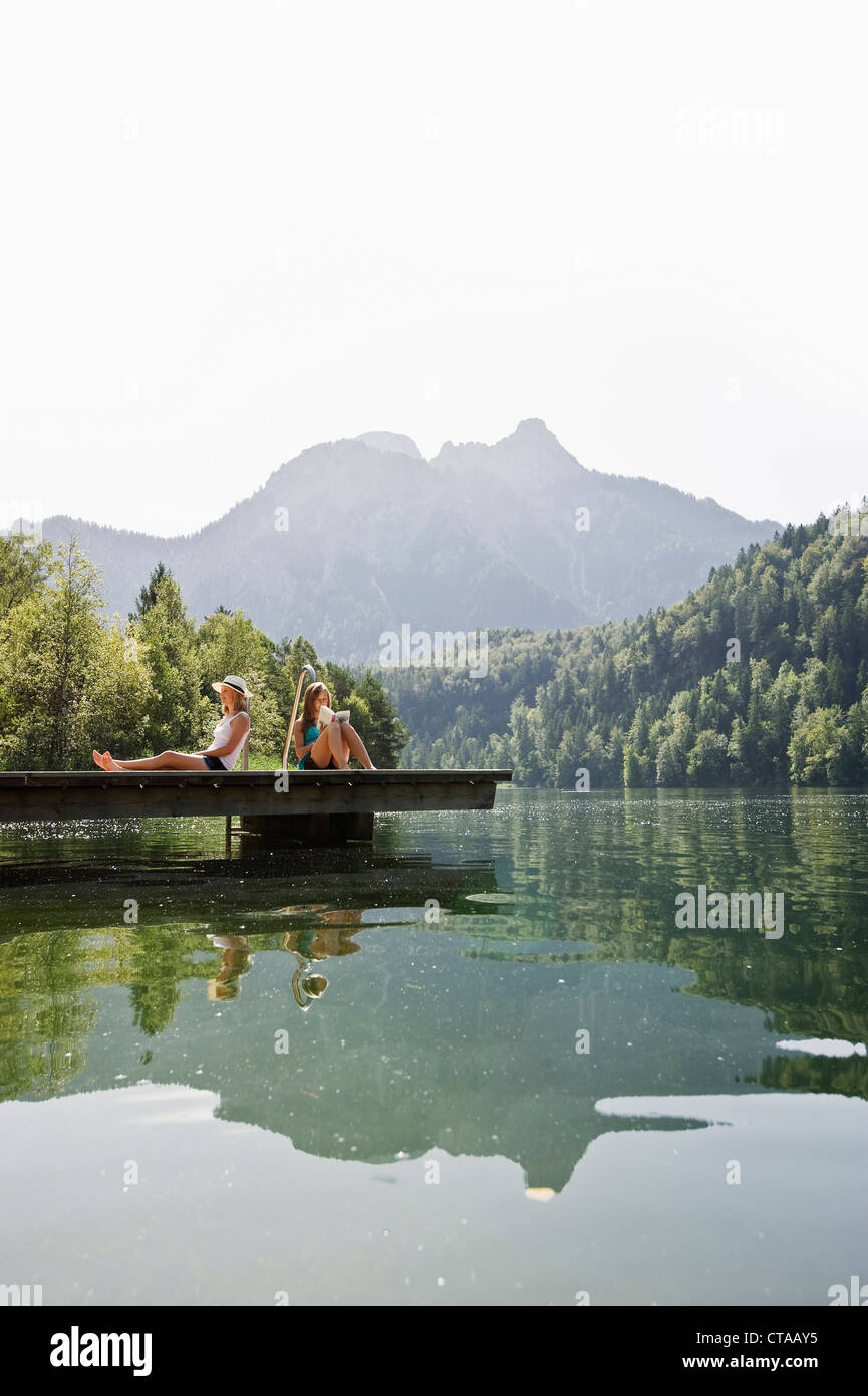 Zwei Mädchen im Teenageralter sitzt auf einem Jetta am See Schwansee, Schwangau, Allgäu, Bayern, Deutschland Stockfoto