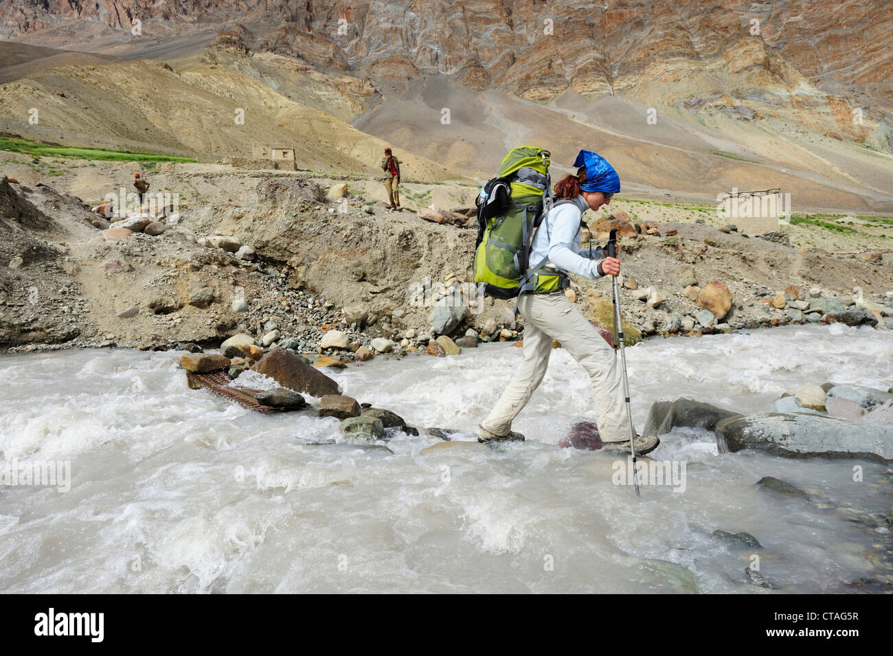 Frau Kreuzung Fluß auf Felsen, Photoksar, Zanskar Bereich durchqueren, Zanskar Range, Zanskar, Ladakh, Jammu und Kaschmir, Indien Stockfoto