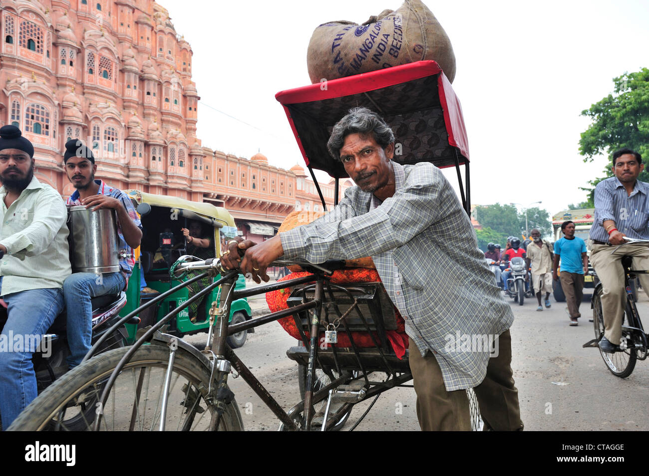 Mann schob geladen Rikscha vor Palast der Winde, Palast der Winde, Hawa Mahal, Jaipur, Rajasthan, Indien Stockfoto