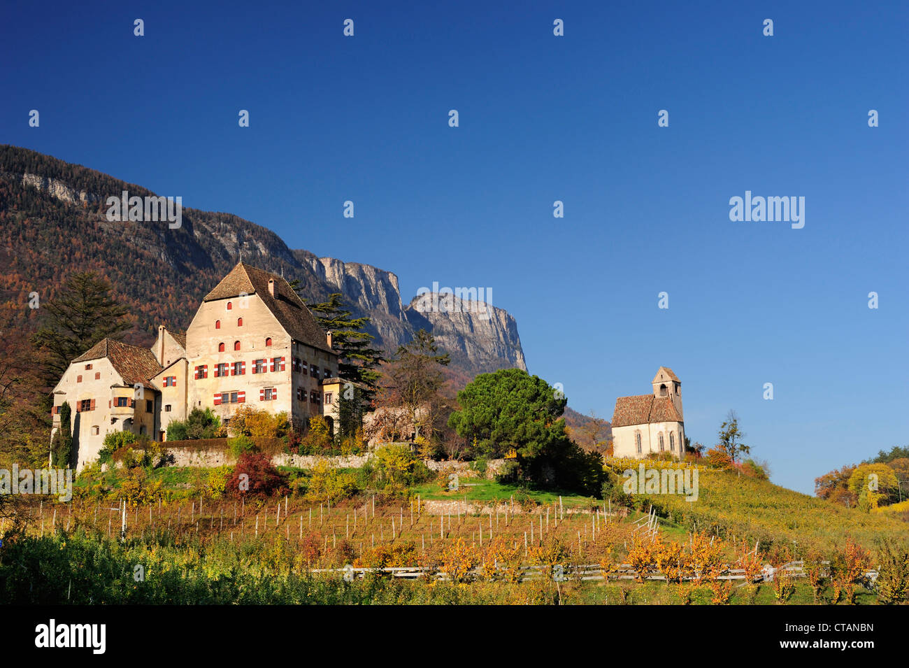 Sehen, Herrenhaus und Kirche in den Weinbergen in herbstlichen Farben mit Felswand im Hintergrund, in der Nähe Kalterer See, Südtirol, Italien, E Stockfoto