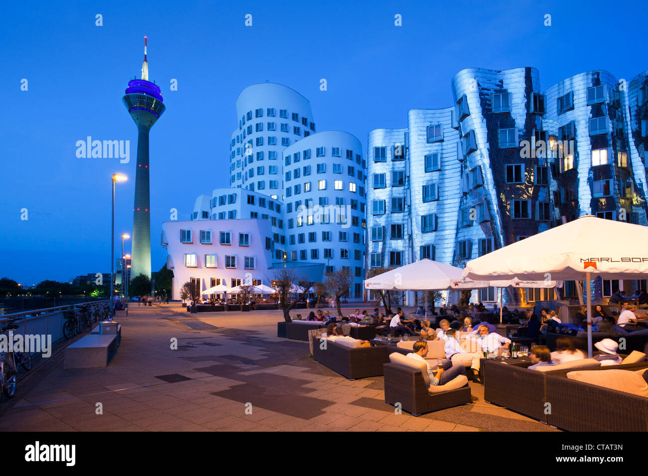 Restaurant-Terrasse, Gehry-Bauten und Rheinturm Turm am Abend, Neuer Zollhof (Architekt: F.O Gehry), Medienhafen, Du Stockfoto